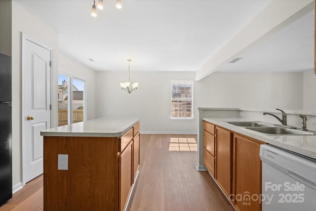 kitchen with white dishwasher, a kitchen island, light countertops, brown cabinetry, and pendant lighting