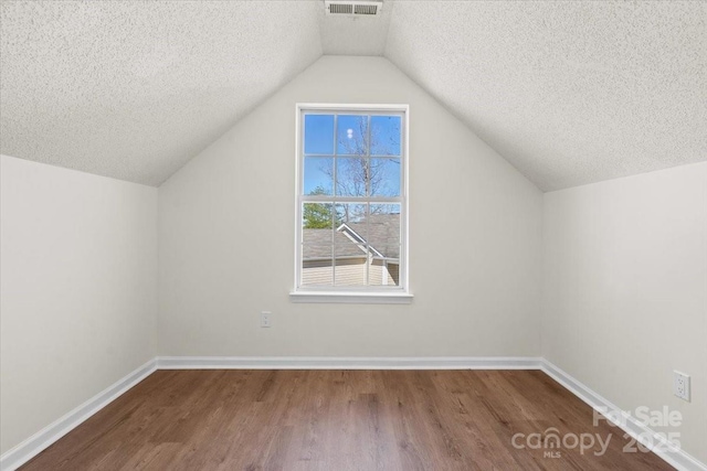 bonus room featuring vaulted ceiling, a textured ceiling, wood finished floors, and baseboards