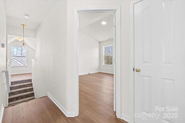 corridor with a textured ceiling, wood finished floors, and baseboards