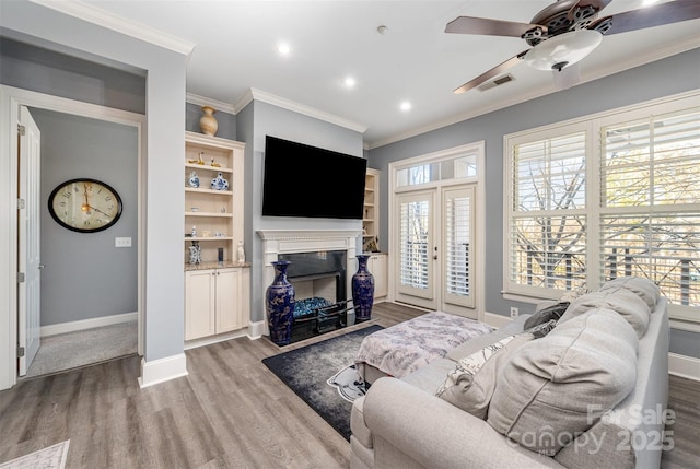 living area featuring ornamental molding, plenty of natural light, wood finished floors, and visible vents