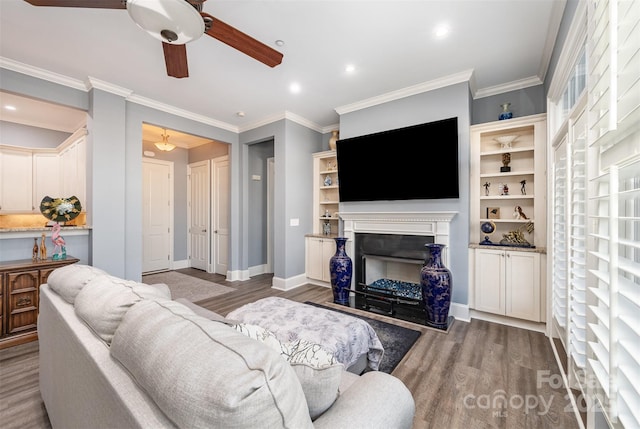 living area with a fireplace with flush hearth, wood finished floors, a ceiling fan, baseboards, and ornamental molding