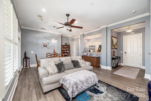 living room with crown molding, baseboards, and wood finished floors