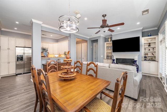 dining area featuring a fireplace, ornamental molding, wood finished floors, and recessed lighting