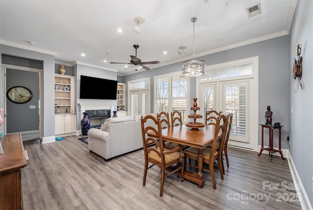 dining room with baseboards, light wood-type flooring, a fireplace, and crown molding