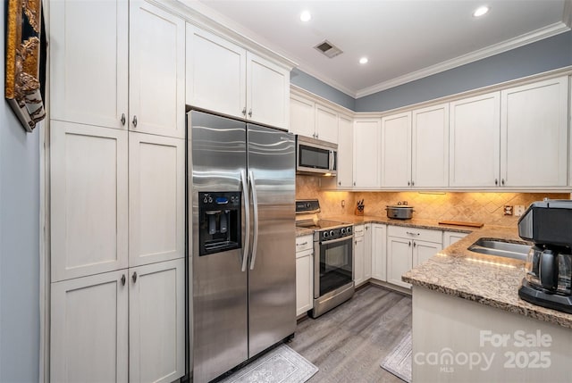 kitchen featuring stainless steel appliances, visible vents, light wood-style floors, backsplash, and crown molding