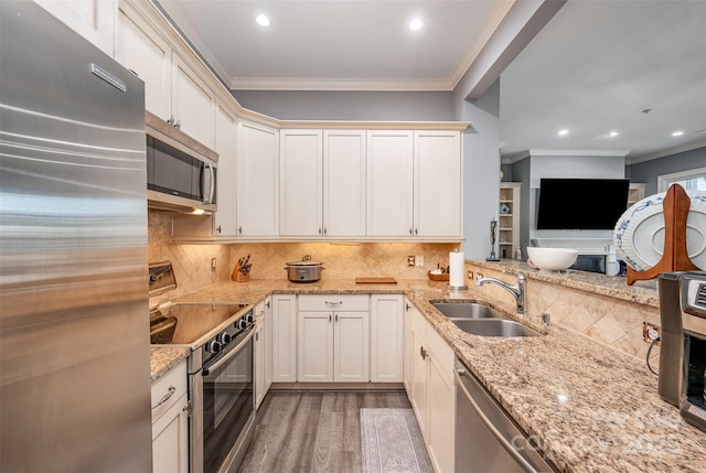 kitchen with appliances with stainless steel finishes, a sink, light wood-style flooring, and crown molding