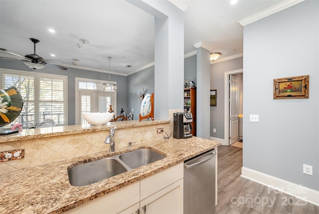 kitchen featuring light wood finished floors, light stone counters, ornamental molding, stainless steel dishwasher, and a sink