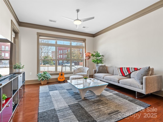 living room with a ceiling fan, wood finished floors, visible vents, and crown molding