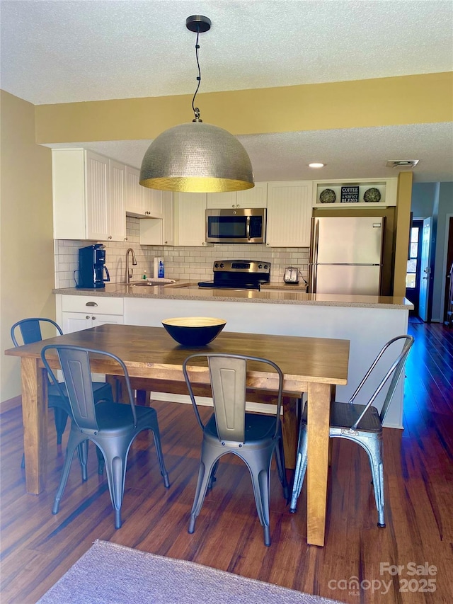 dining area with dark wood finished floors, visible vents, and a textured ceiling