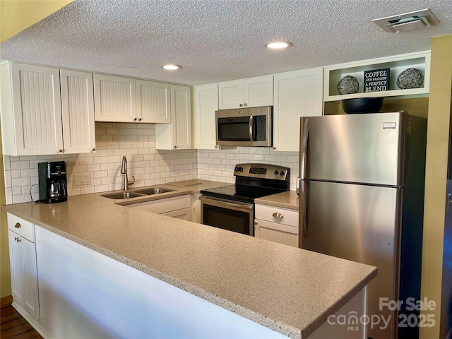 kitchen with visible vents, a sink, white cabinets, stainless steel appliances, and open shelves