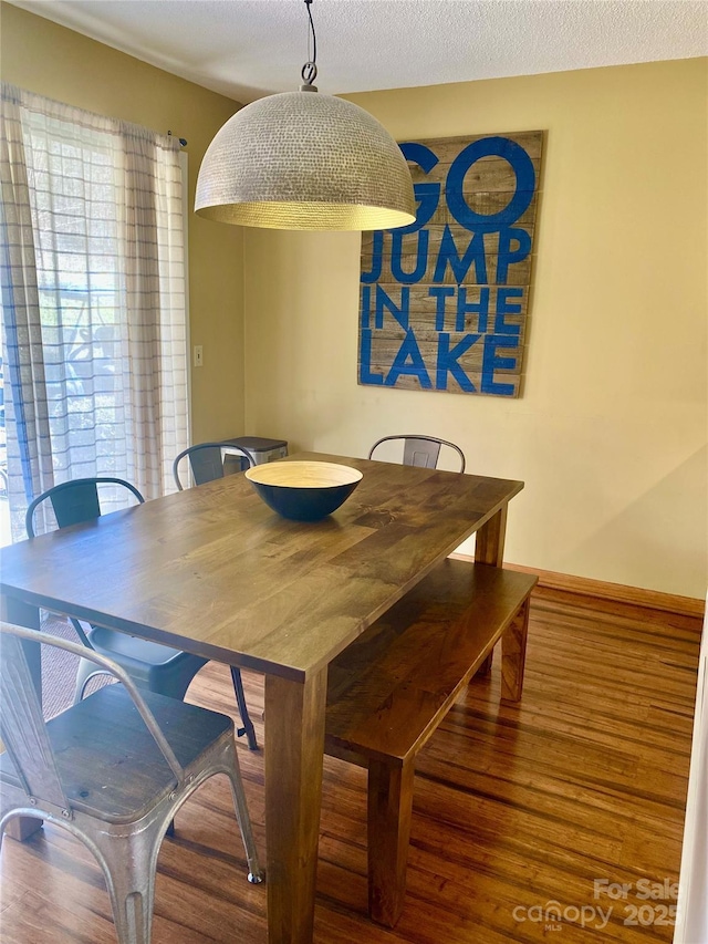 dining area with a textured ceiling and wood finished floors