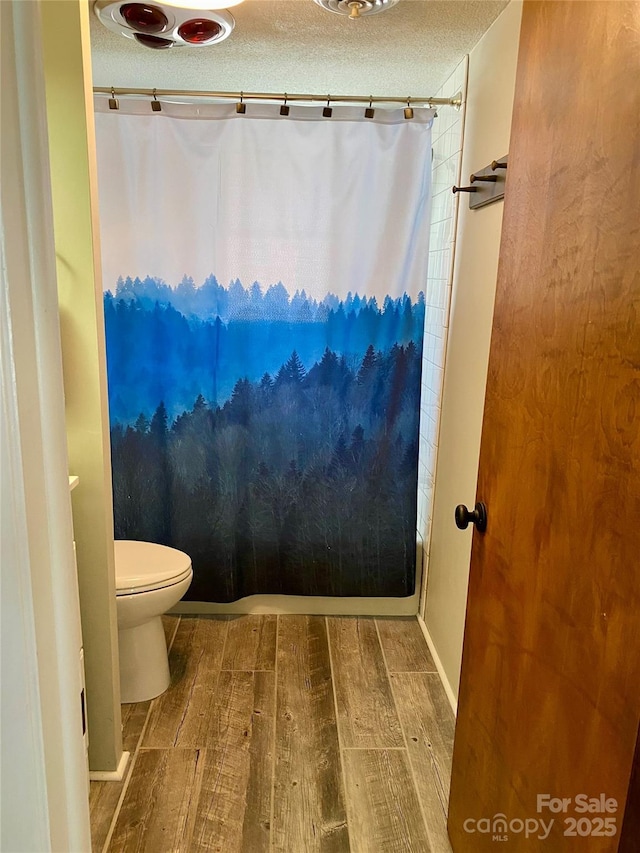 full bathroom with toilet, a textured ceiling, shower / tub combo, and wood finish floors