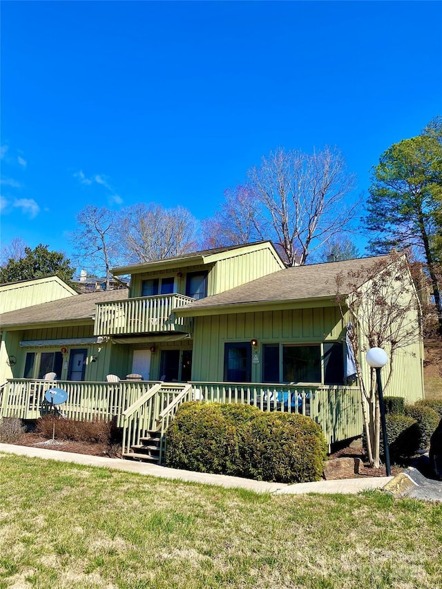 exterior space with a balcony, a porch, a front lawn, and a shingled roof