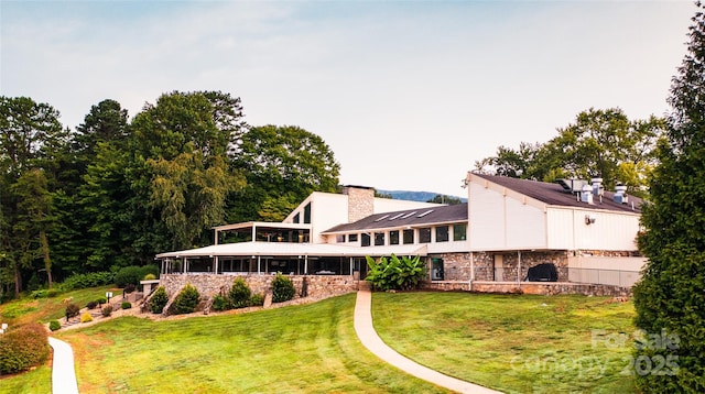 rear view of property featuring a lawn and a chimney