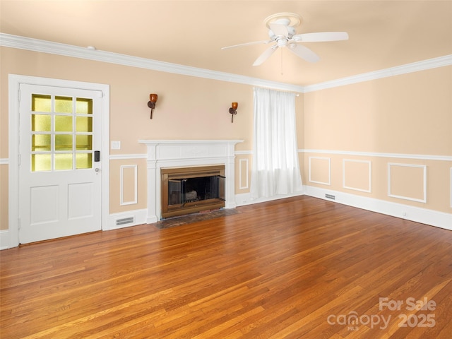 unfurnished living room featuring a fireplace with flush hearth, visible vents, ornamental molding, and wood finished floors