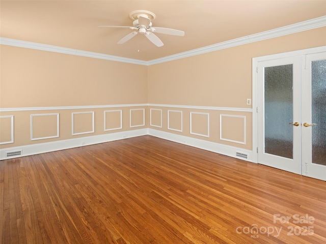 spare room with ornamental molding, wood finished floors, and visible vents