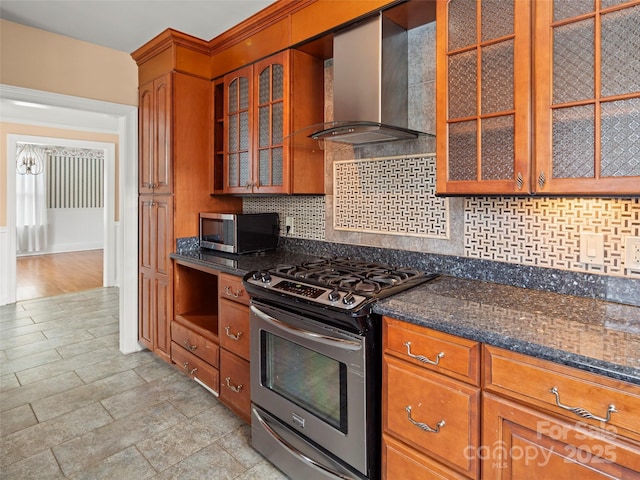 kitchen with stainless steel appliances, wall chimney range hood, backsplash, and glass insert cabinets