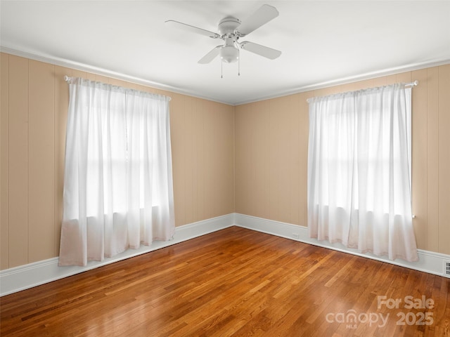 spare room featuring ceiling fan, wood finished floors, and baseboards