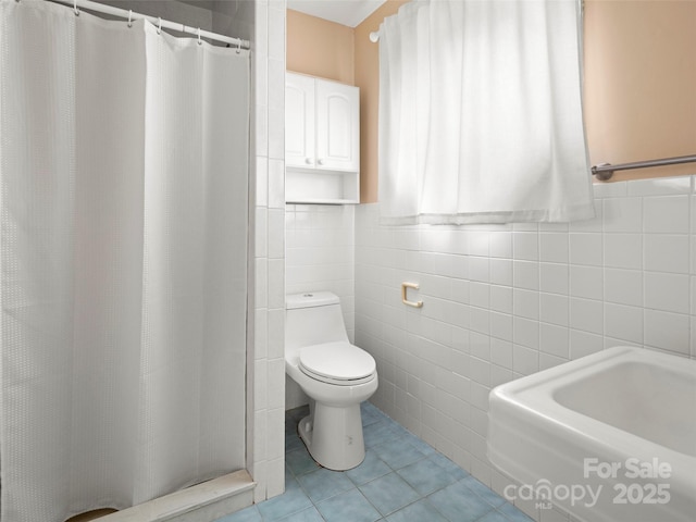 bathroom featuring toilet, curtained shower, tile walls, and tile patterned floors