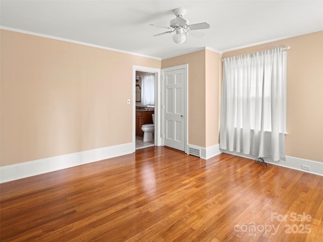 spare room featuring ornamental molding, visible vents, baseboards, and wood finished floors