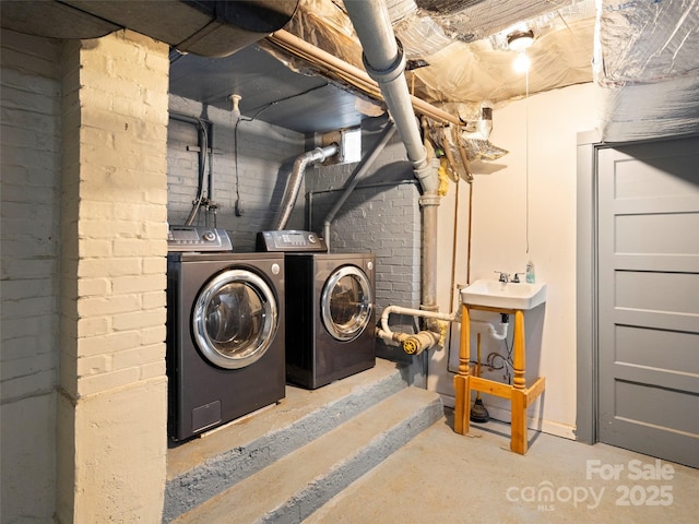 interior space featuring laundry area, brick wall, and separate washer and dryer