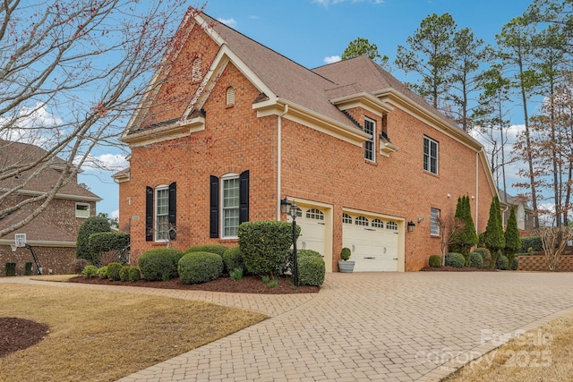 view of property exterior with decorative driveway, brick siding, and a garage