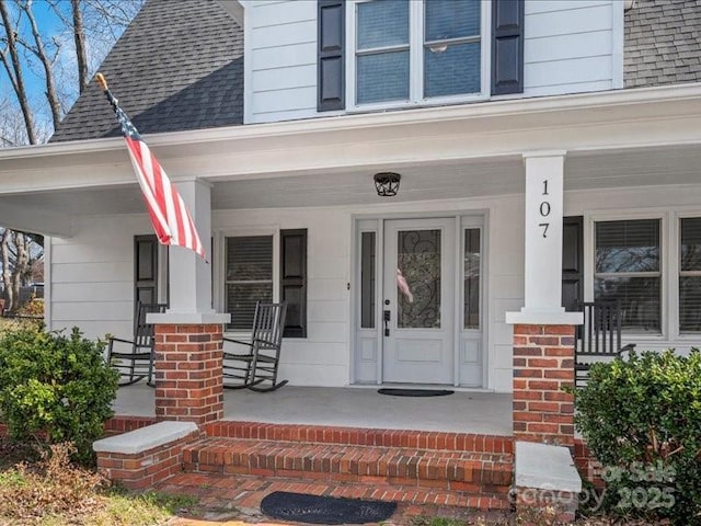 property entrance featuring a shingled roof and a porch