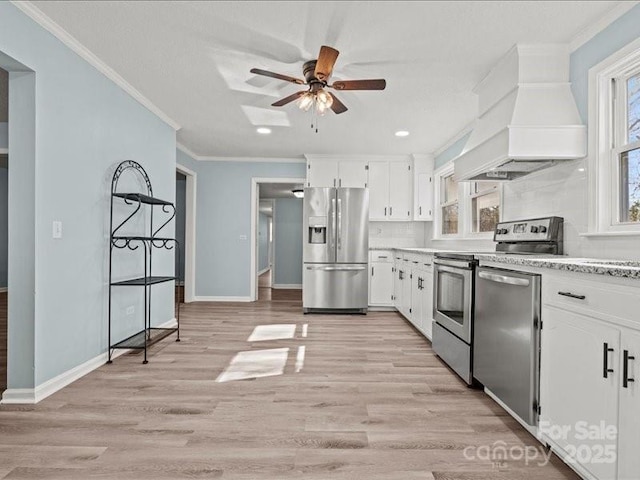 kitchen featuring stainless steel appliances, white cabinets, custom range hood, and ornamental molding