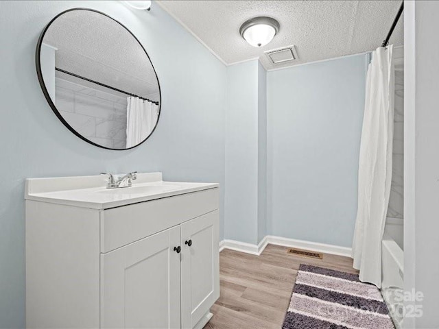 full bathroom with visible vents, a textured ceiling, vanity, and wood finished floors