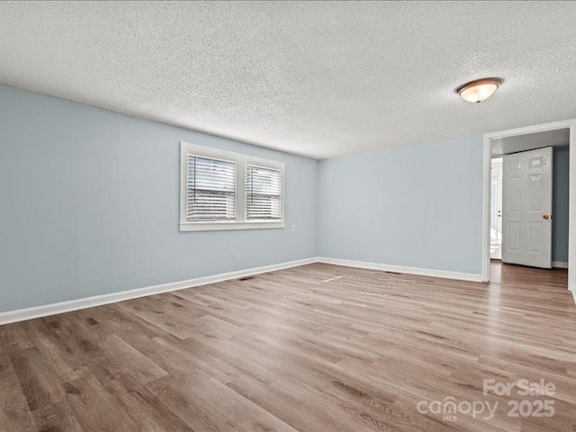 spare room featuring a textured ceiling, baseboards, and wood finished floors