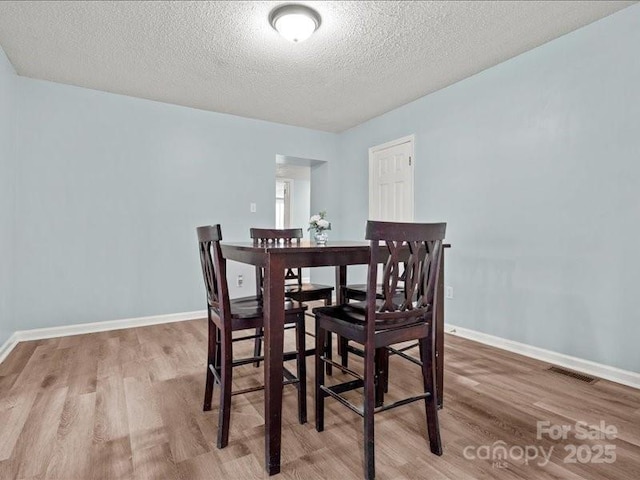 dining room with baseboards, visible vents, and wood finished floors