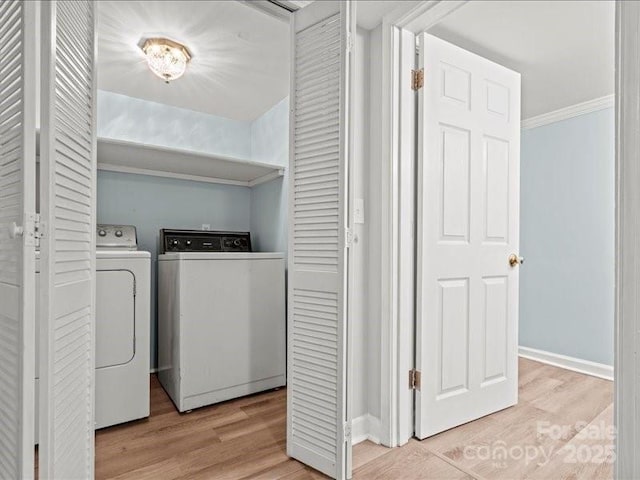 clothes washing area with crown molding, washing machine and clothes dryer, light wood-type flooring, laundry area, and baseboards