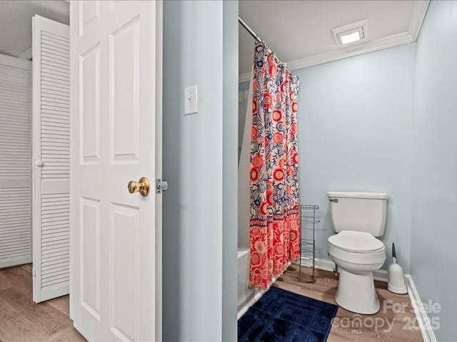 bathroom featuring ornamental molding, wood finished floors, toilet, and shower / tub combo with curtain