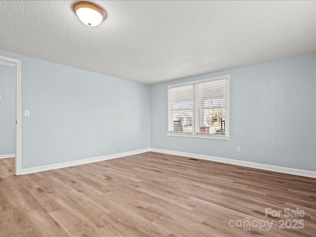 unfurnished room featuring a textured ceiling, baseboards, and wood finished floors