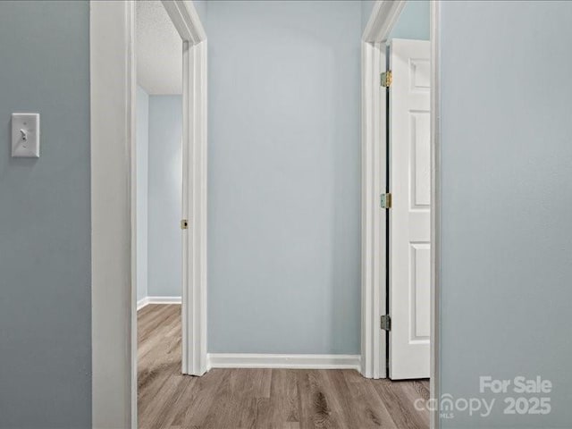 hallway featuring baseboards and wood finished floors