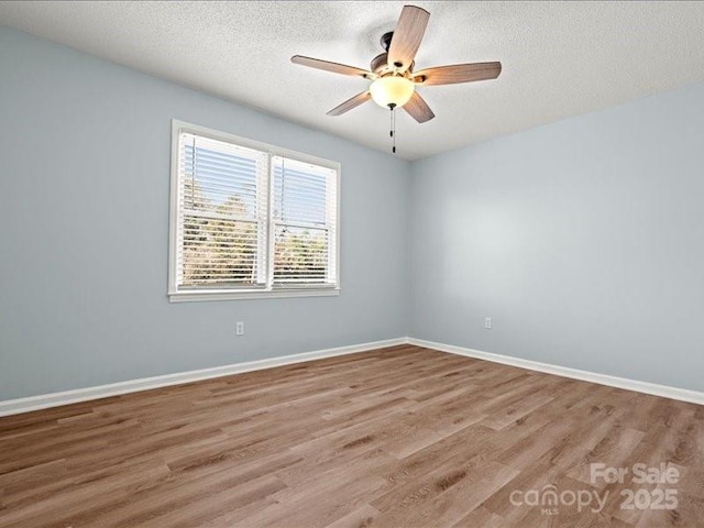 unfurnished room with a textured ceiling, light wood-style flooring, and baseboards