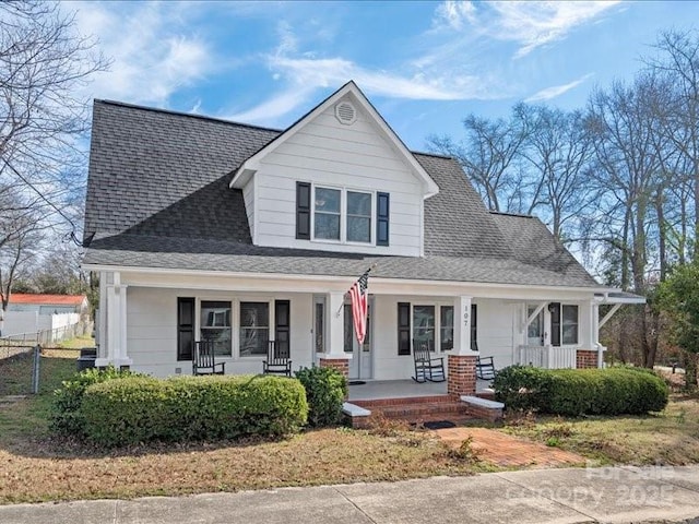 view of front of home featuring a shingled roof, fence, and a porch