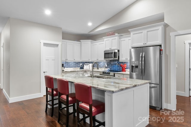 kitchen featuring backsplash, appliances with stainless steel finishes, white cabinetry, and lofted ceiling