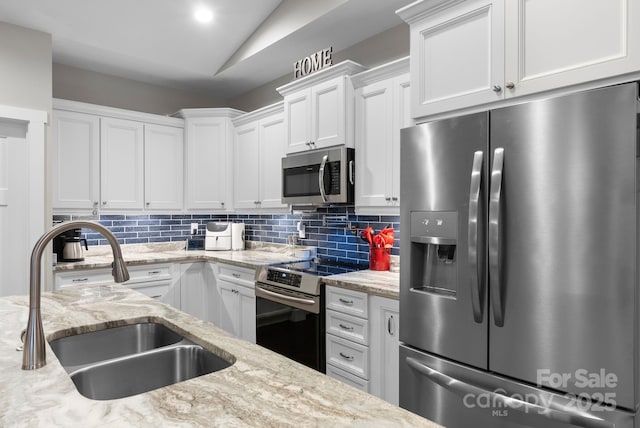 kitchen with a sink, tasteful backsplash, white cabinetry, stainless steel appliances, and lofted ceiling