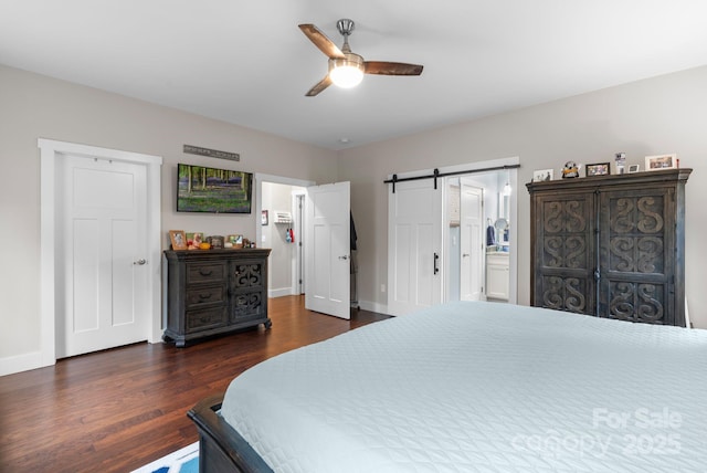 bedroom with ceiling fan, a barn door, baseboards, and dark wood finished floors