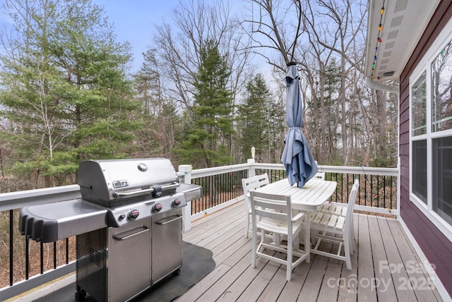 wooden terrace featuring outdoor dining area and a grill