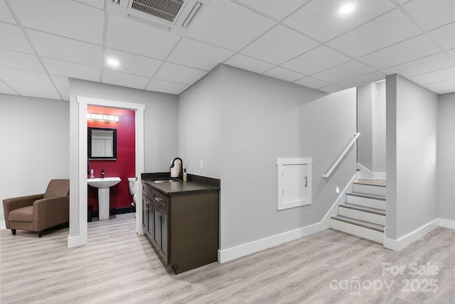 bar featuring stairway, baseboards, visible vents, light wood-style flooring, and a sink