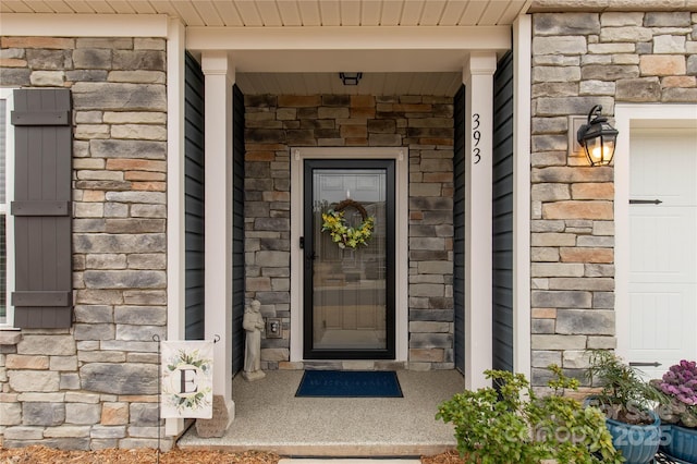 property entrance with a garage and stone siding