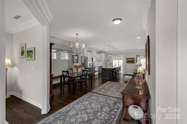 interior space featuring dark wood-style floors, plenty of natural light, visible vents, and crown molding