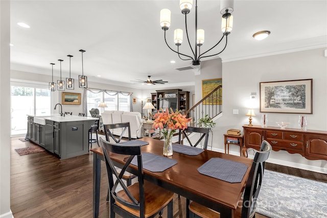 dining room featuring dark wood-style flooring, crown molding, stairway, baseboards, and ceiling fan with notable chandelier