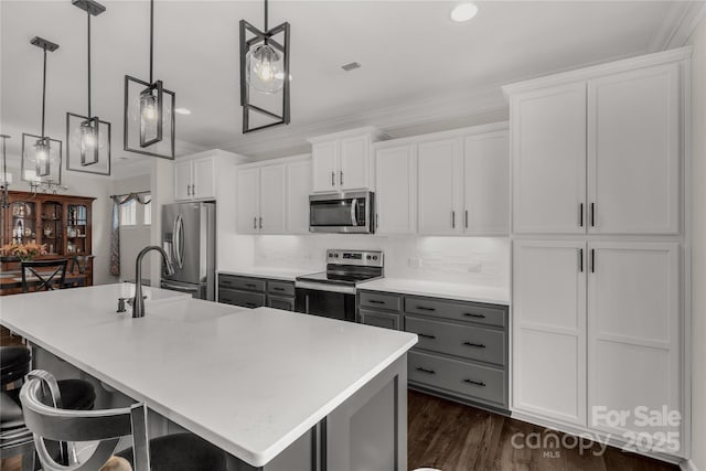 kitchen featuring stainless steel appliances, a sink, visible vents, gray cabinets, and a center island with sink