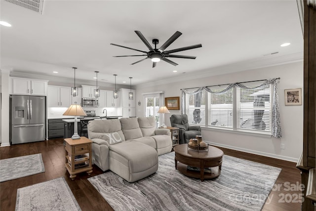 living area featuring recessed lighting, dark wood-type flooring, visible vents, baseboards, and crown molding