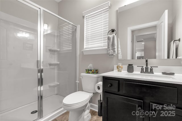 full bathroom with toilet, a stall shower, baseboards, and vanity