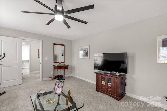 living room featuring light carpet, a healthy amount of sunlight, baseboards, and a ceiling fan