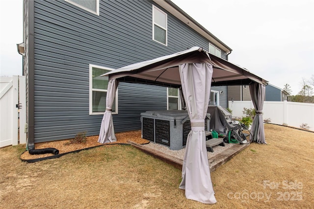 back of property with fence, a gazebo, and a lawn